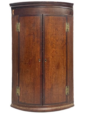 Lot 192 - A George III oak and mahogany banded bow front corner cupboard.