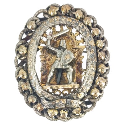 Lot 256 - A silver and gilt medieval revival large brooch with central applied knight under a gilded arch.