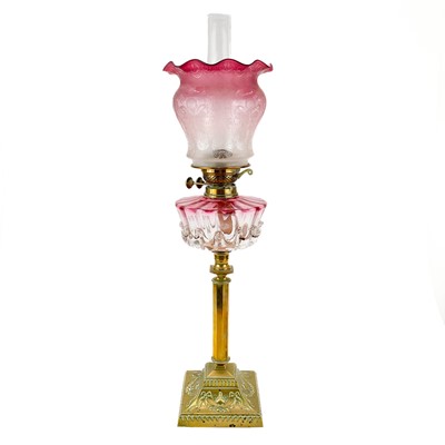 Lot 47 - A Victorian brass oil lamp with a glass oil reservoir and cranberry shade.