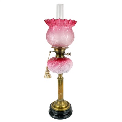 Lot 115 - A Victorian brass oil lamp with a glass oil reservoir and cranberry shade.