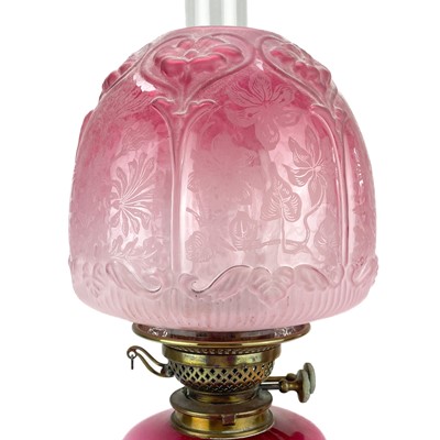 Lot 190 - A Victorian brass oil lamp with a pink glass reservoir and cranberry shade.