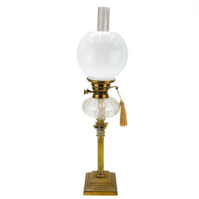 Lot 21 - A Victorian brass oil lamp with a clear glass oil reservoir and white glass shade.