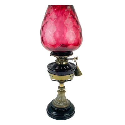 Lot 205 - A Victorian brass oil lamp with a cranberry glass shade.