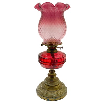 Lot 26 - A Victorian brass oil lamp with a cranberry glass shade.