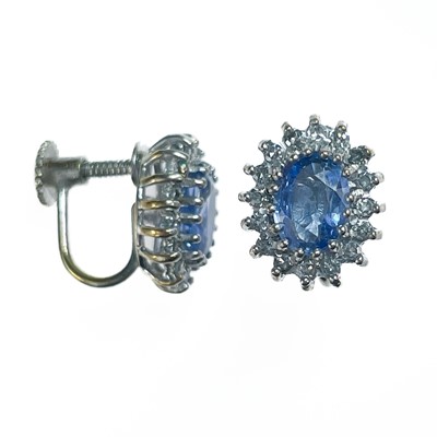 Lot 193 - A pair of 9ct white gold oval cornflower blue sapphire and diamond cluster screw back earrings.