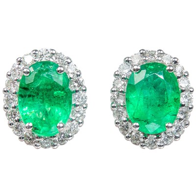 Lot 350 - A pair of 18ct white gold oval emerald and diamond cluster stud earrings.