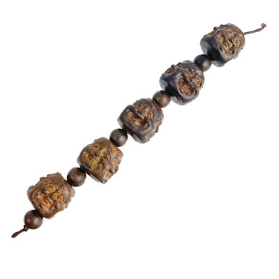 Lot 1089 - A strand of five Chinese carved hardwood Buddha head beads.