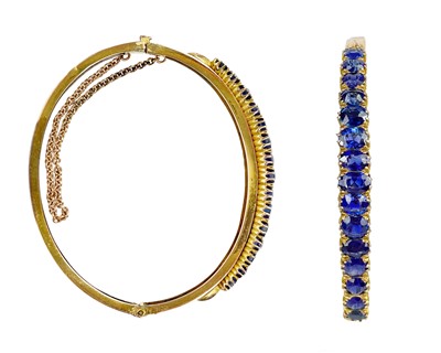 Lot 117 - An early 20th-century gold (tests 9ct) blue sapphire set hinged bangle.