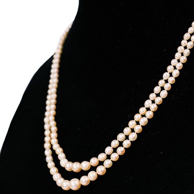 Lot 38 - A double-strand graduated cultured pearl necklace with three-stone diamond clasp.