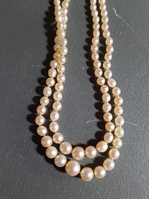 Lot 38 - A double-strand graduated cultured pearl necklace with three-stone diamond clasp.