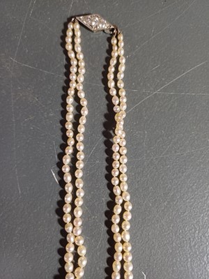 Lot 38 - A double-strand graduated cultured pearl necklace with three-stone diamond clasp.