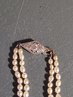 Lot 38 - A double-strand graduated cultured pearl necklace with three-stone diamond clasp.