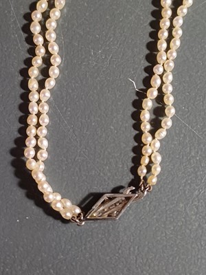 Lot 38 - A double-strand graduated cultured pearl necklace with three-stone diamond clasp.