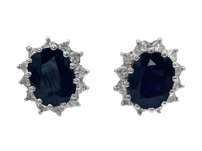 Lot 38 - An 18ct white gold diamond and sapphire cluster ring with a pair of matching earrings.