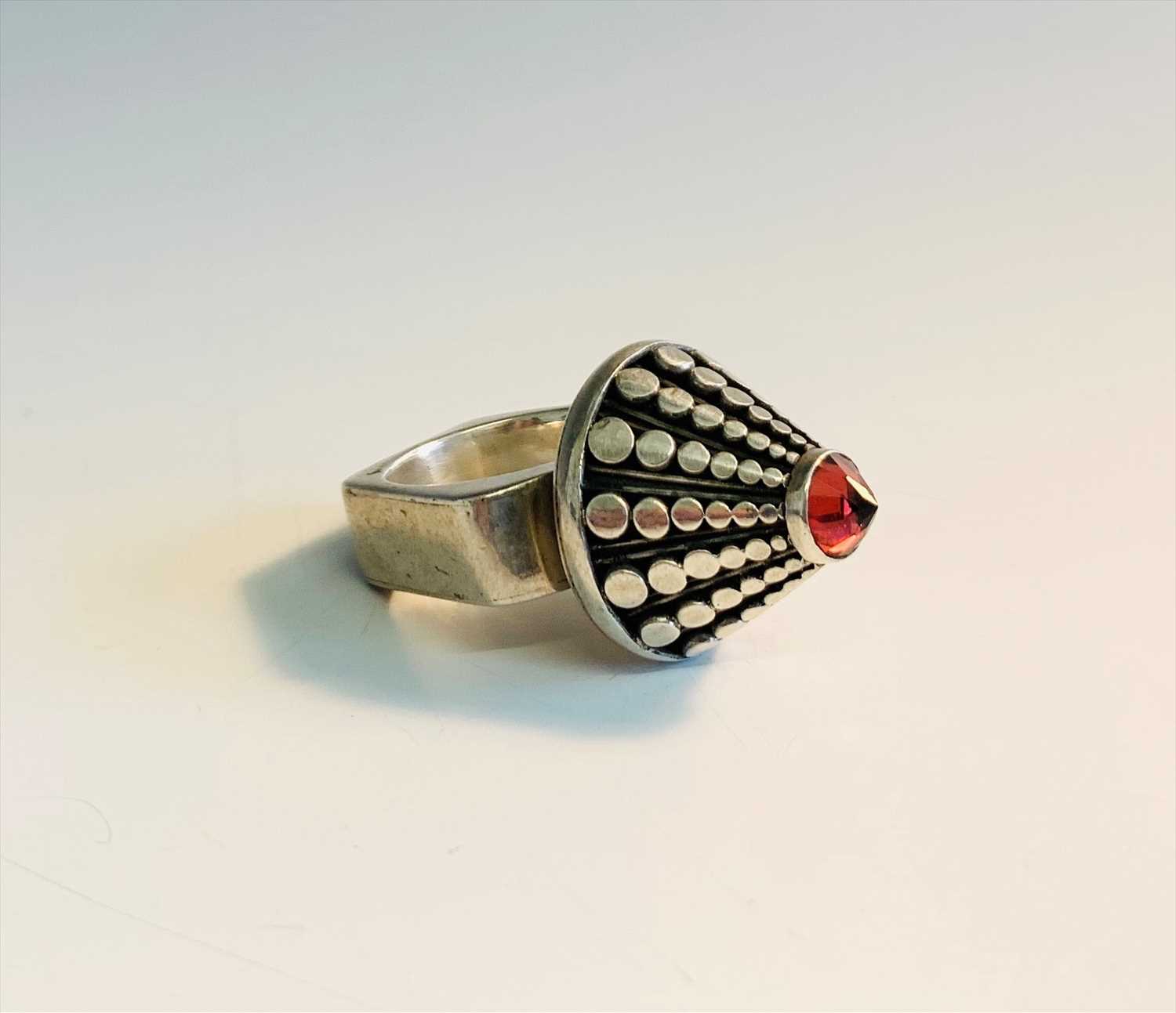 Lot 2541 - A Modernist silver cone ring set a red stone.