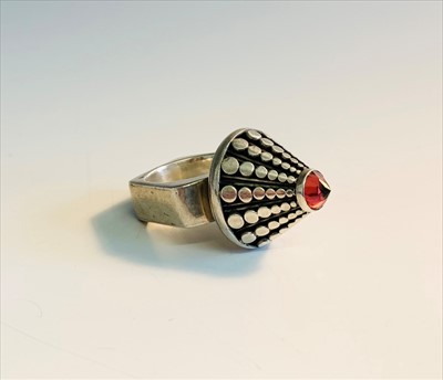 Lot 2541 - A Modernist silver cone ring set a red stone.