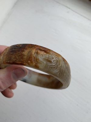 Lot 22 - A Chinese carved jade bangle, probably Neolithic period.