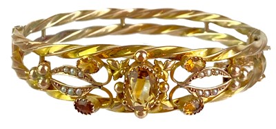 Lot 11 - An Edwardian 9ct gold citrine and seed pearl set hinged bangle.