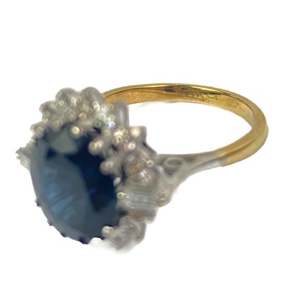 Lot 132 - An 18ct oval blue sapphire and diamond cluster ring.