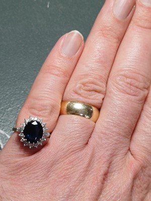 Lot 132 - An 18ct oval blue sapphire and diamond cluster ring.