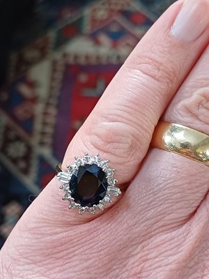 Lot 132 - An 18ct oval blue sapphire and diamond cluster ring.