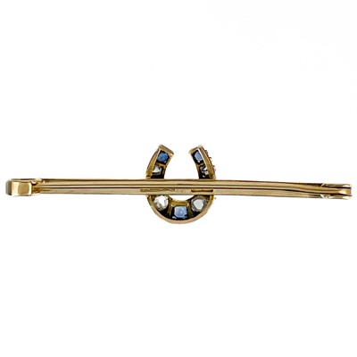 Lot 194 - A 9ct diamond and sapphire set horseshoe bar brooch and a 9ct ruby set floral brooch.