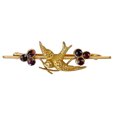 Lot 112 - A 15ct gold garnet set swallow bird applied bar brooch.