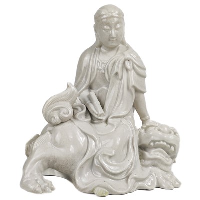 Lot 1341 - A Chinese blanc de chine figure of Guanyin upon a dog of fo.