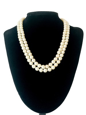 Lot 230 - A cultured pearl double-strand necklace with 9ct synthetic blue sapphire and white spinel clasp.