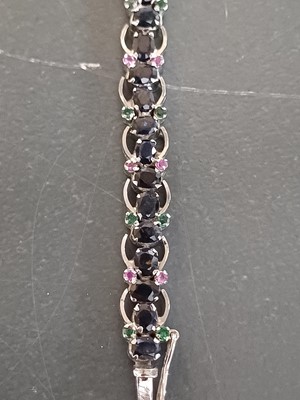 Lot 82 - A contemporary 925 silver sapphire bracelet with emerald and ruby accents.