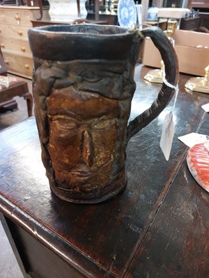 Lot 182 - An early 20th century folk art leather twin handled two faced tankard.