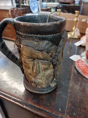 Lot 182 - An early 20th century folk art leather twin handled two faced tankard.