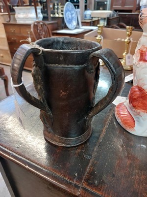 Lot 182 - An early 20th century folk art leather twin handled two faced tankard.