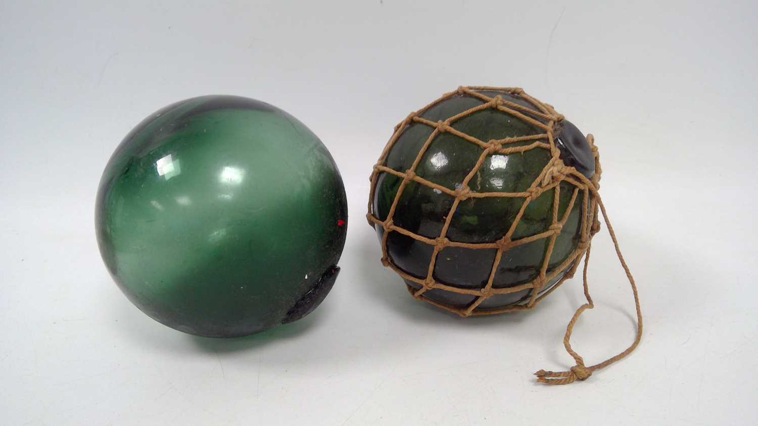Lot 62 - Two green glass fishing floats, one still