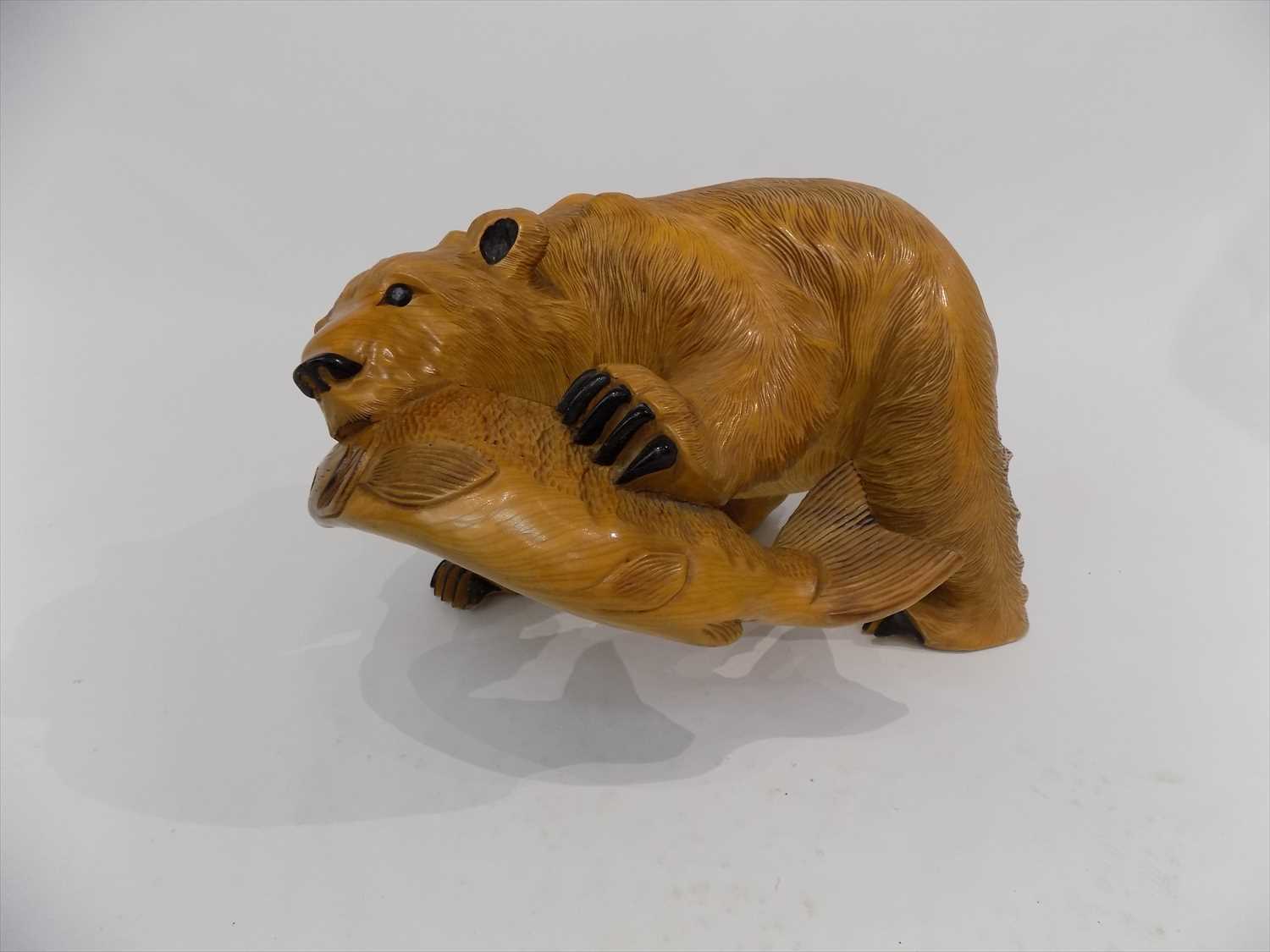 Lot 40 - A carved wood sculpture of a bear with a fish...