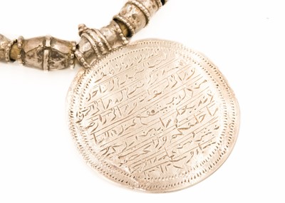 Lot 62 - An Omani silver amulet with four coins.
