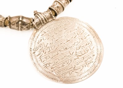 Lot 104 - An Omani silver amulet with four coins.