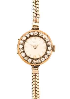 Lot 107 - An early 20th century 18ct cased lady's gold manual wristwatch with diamond set bezel, on a 9ct bracelet.