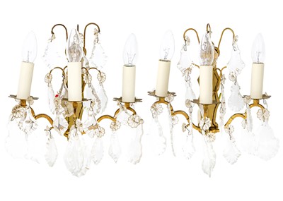 Lot 84 - A pair of brass and cut glass triple wall lights.