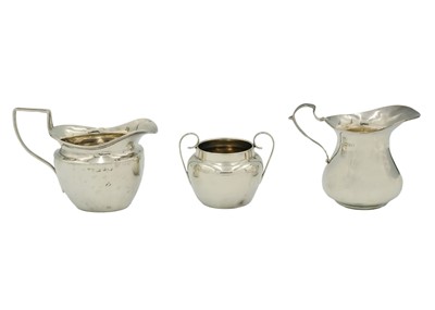 Lot 177 - Two silver cream jugs and a twin-handled sugar bowl.