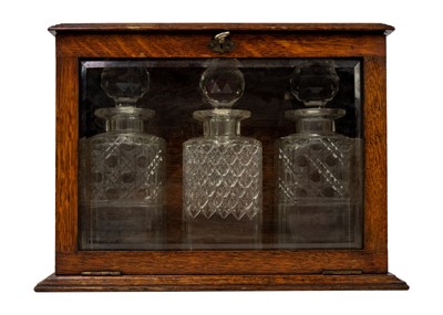 Lot 1424 - An oak glazed tantalus circa 1900.