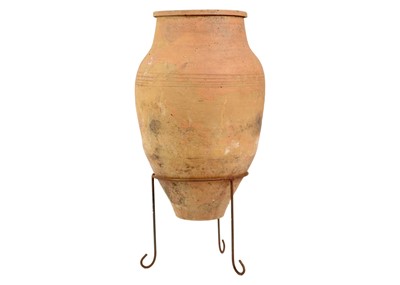 Lot 118 - A terracotta olive jar on metal stand.