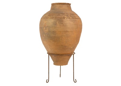 Lot 119 - A terracotta olive jar on metal stand.