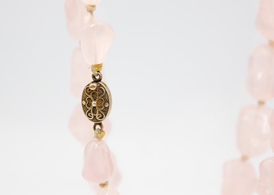 Lot 19 - A Chinese rose quartz irregular bead necklace with silver gilt filigree clasp.