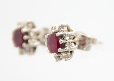 Lot 14 - A 14ct white gold ruby and diamond set cluster ring with matching stud earrings.
