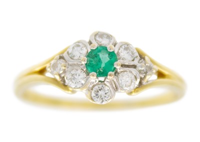 Lot 78 - A modern 18ct diamond and emerald set cluster ring.