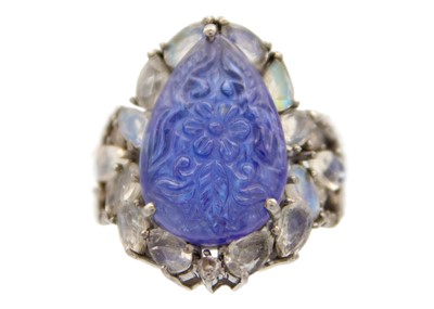 Lot 144 - An unusual silver ring set with a carved pear-shaped Tanzanite, surrounded by moonstone.