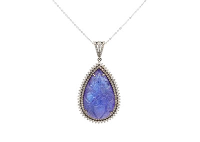 Lot 143 - A large white metal pendant set with a carved pear shaped carved Tanzanite and diamonds.