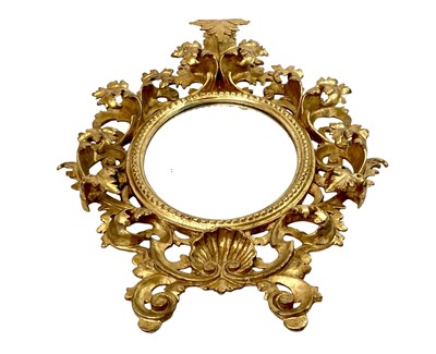 Lot 322 - An ornate Florentine oval giltwood rococo style wall mirror.