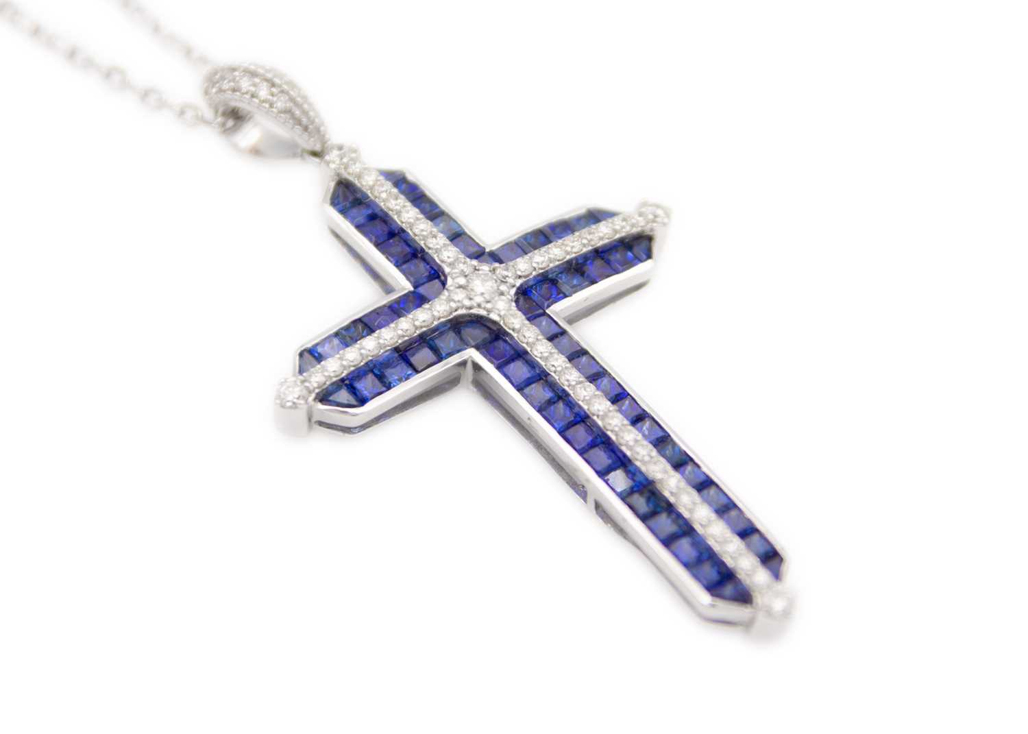 Lot 124 - A stylish 18ct white gold diamond and sapphire set cross pendant necklace.